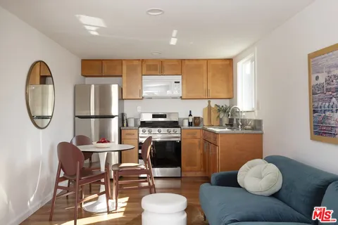 a kitchen with stainless steel appliances granite countertop a stove top oven a sink a dining table and chairs with wooden floor