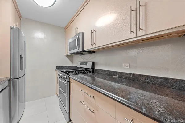 a kitchen with granite countertop a sink a stove and refrigerator