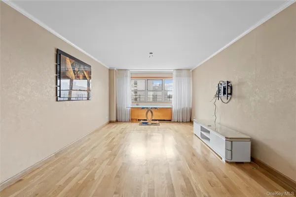 a view of an empty room with a window and wooden floor