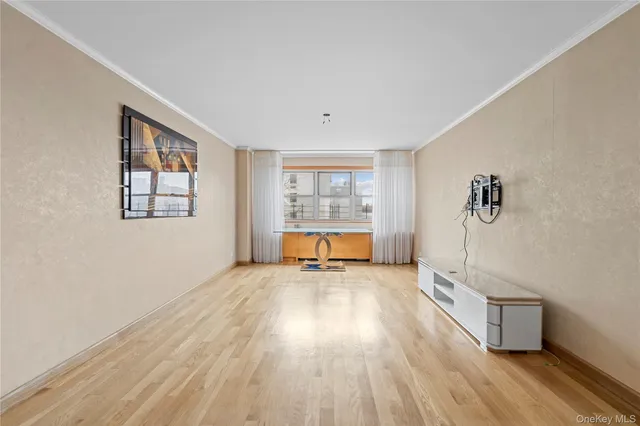 a view of an empty room with a window and wooden floor