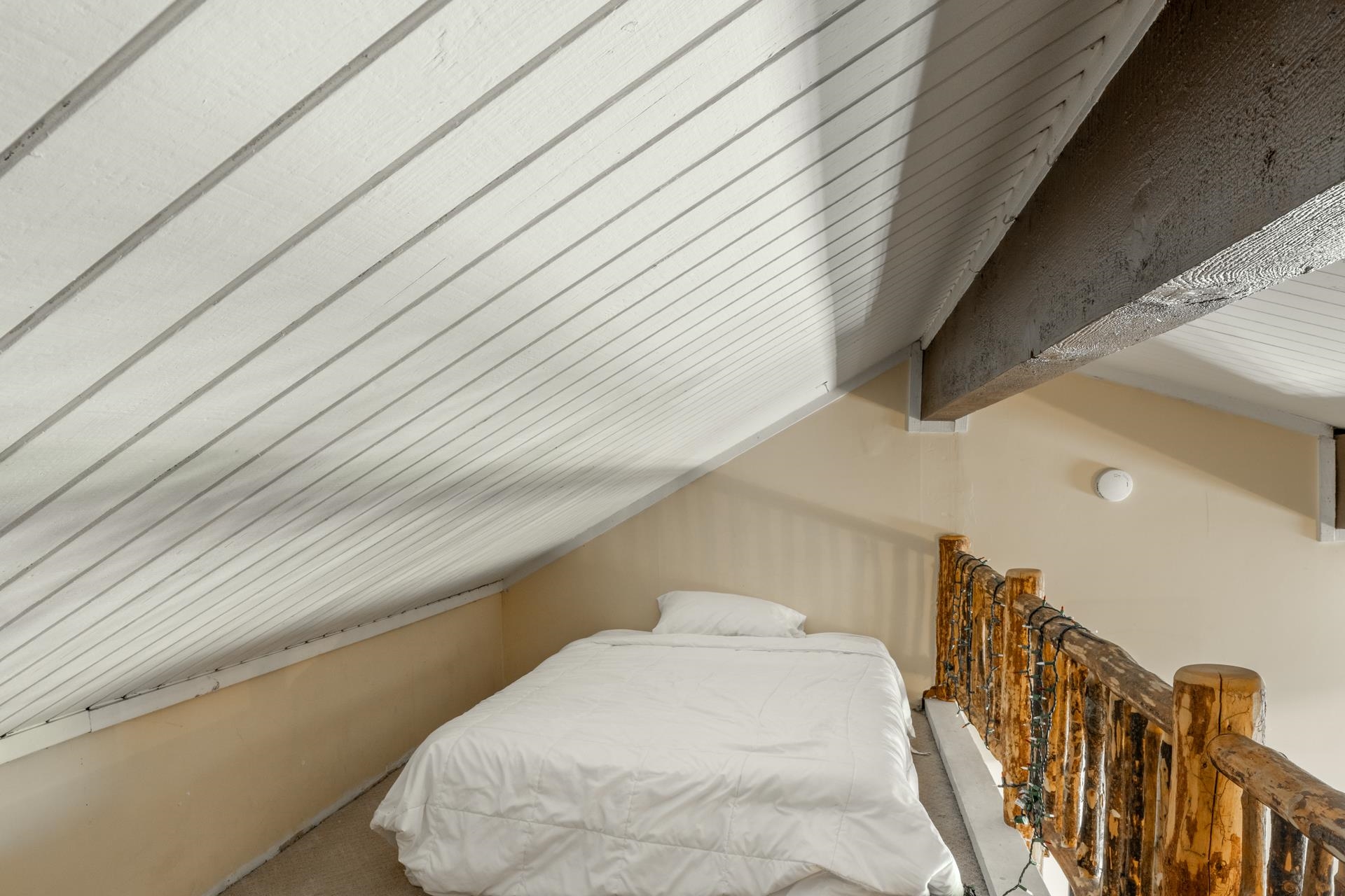 165 Old Mammoth Road, Unit 3 Mammoth Lakes, CA 93546 - Photo 33 of 48 Loft space featuring a sloped, paneled ceiling with exposed wood beams, a distressed wood railing, and neutral-toned wall paint