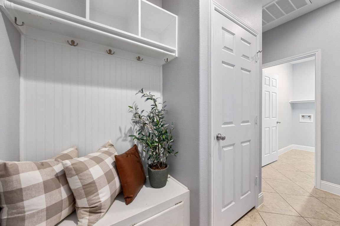 2041 Elaina Loop Leander, TX 78641 - Photo 19 of 25 This welcoming drop zone offers the perfect blend of charm and function, complete with built-in hooks, cozy bench seating (with storage), and easy access to the laundry room just beyond.