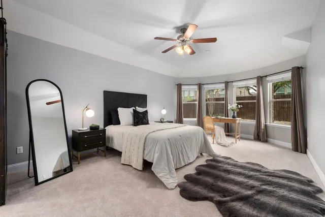 a spacious bedroom with a bed a large mirror with chandelier and glass door