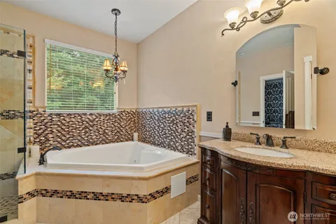a bathroom with a granite countertop sink a mirror a vanity and a bathtub