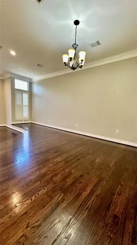 a view of empty room with wooden floor and chandelier