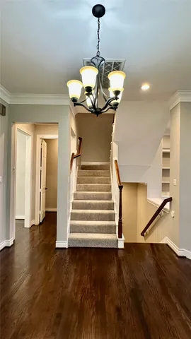 a view of a chandelier fan and entryway with wooden floor
