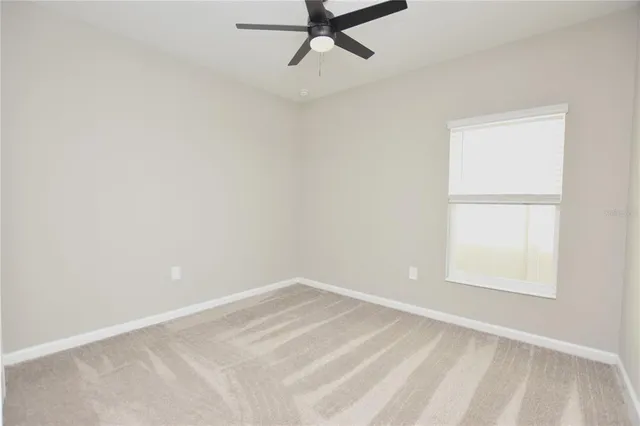 an empty room with a window and a fan