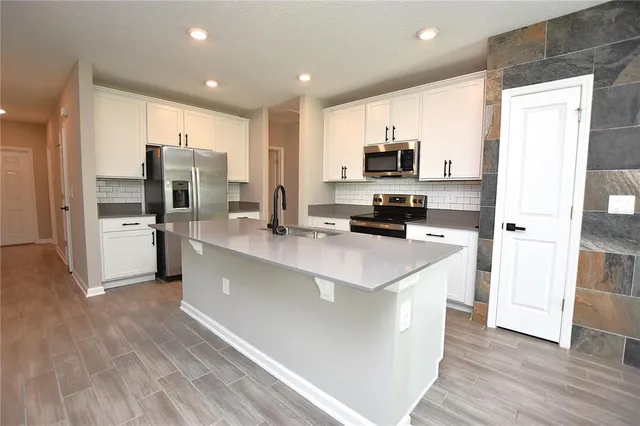 a kitchen with stainless steel appliances a refrigerator and a stove top oven