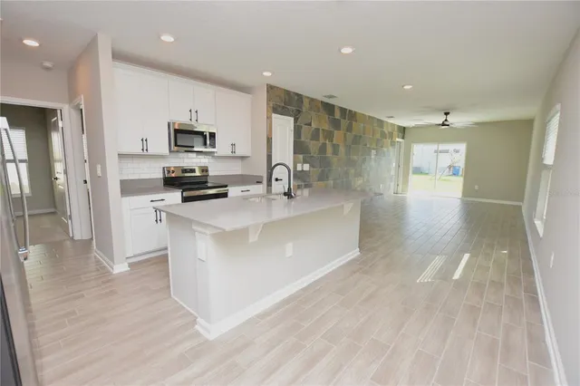 a large white kitchen with kitchen island a sink a stove a refrigerator and white cabinets