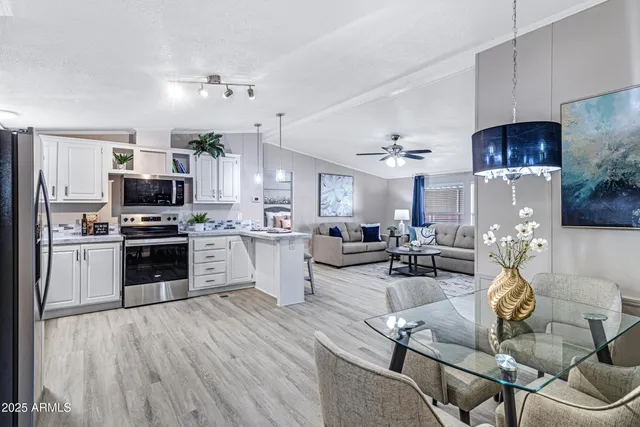a kitchen with stainless steel appliances kitchen island granite countertop a refrigerator a stove a microwave oven a dining table and chairs with wooden floor