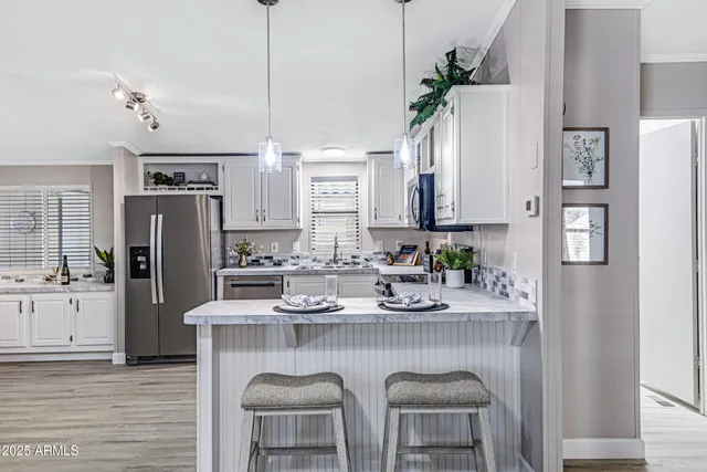 a kitchen with stainless steel appliances granite countertop a table chairs refrigerator and sink