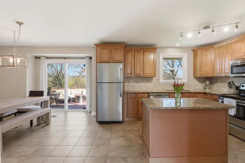 a kitchen with a refrigerator a stove a sink dishwasher with a dining table and chairs