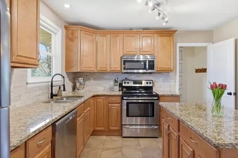 a kitchen with stainless steel appliances granite countertop a sink stove and refrigerator