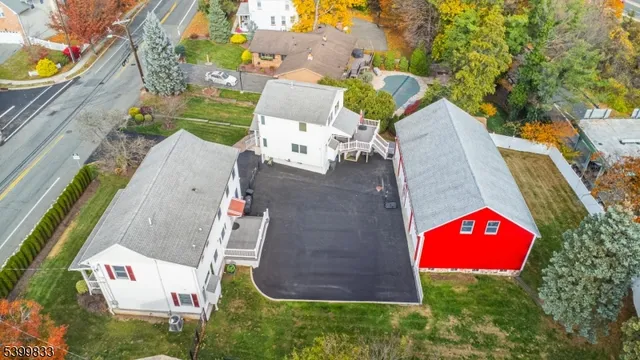 a view of a white house with a small yard and large trees