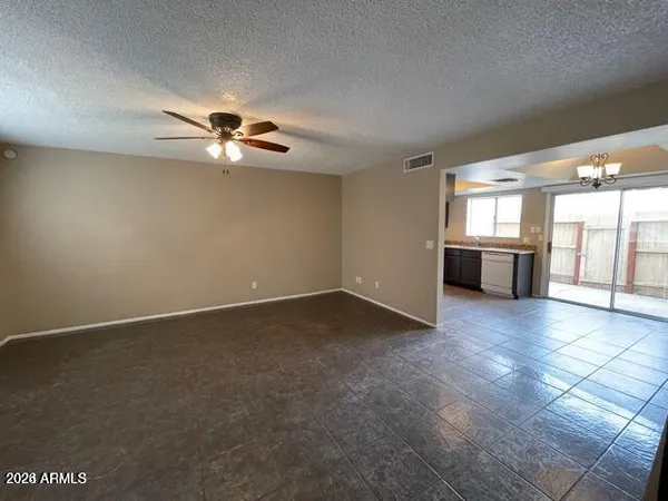 an empty room with chandelier fan and windows