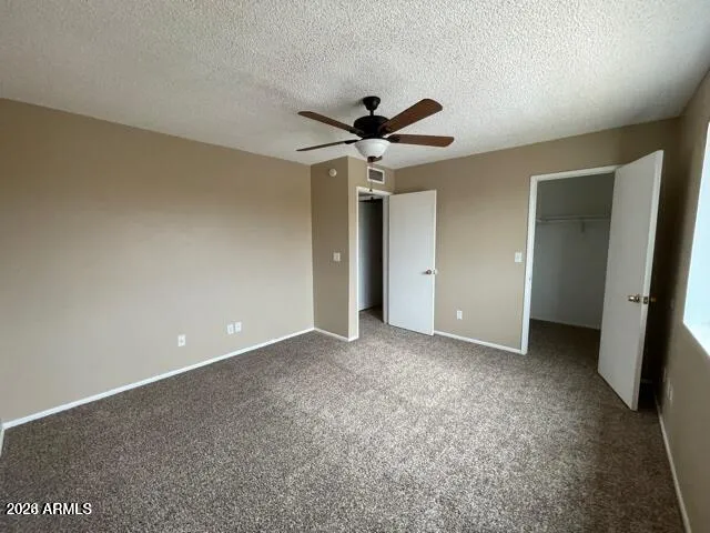 an empty room with a ceiling fan and carpet