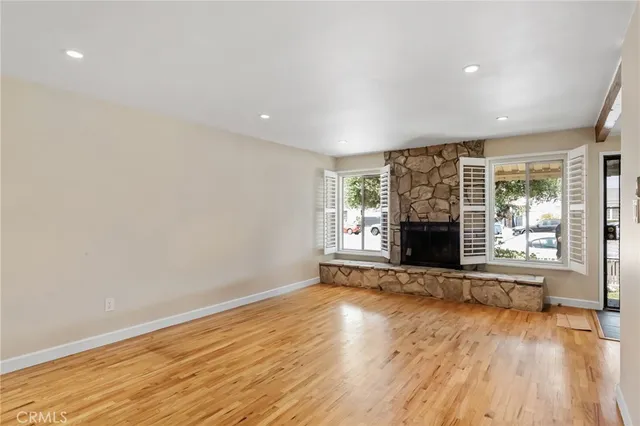 a view of empty room with wooden floor and fireplace