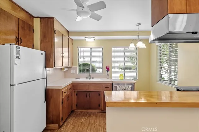 a kitchen with stainless steel appliances granite countertop a refrigerator a sink dishwasher a stove and a dining table with wooden floor