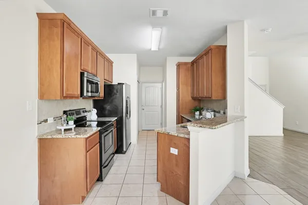 a kitchen with stainless steel appliances granite countertop a stove top oven a refrigerator a sink and dishwasher with wooden cabinets