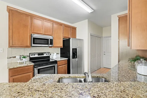 a kitchen with stainless steel appliances kitchen island granite countertop a refrigerator and a stove top oven