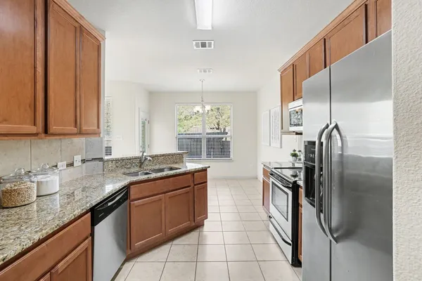a kitchen with granite countertop a sink stainless steel appliances a counter top space and cabinets