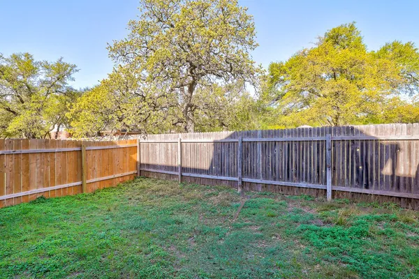 a view of a backyard with a tree and wooden fence