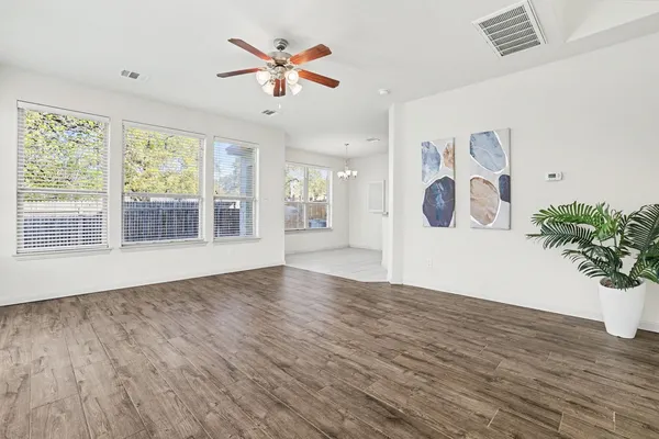 a view of an empty room with window and wooden floor