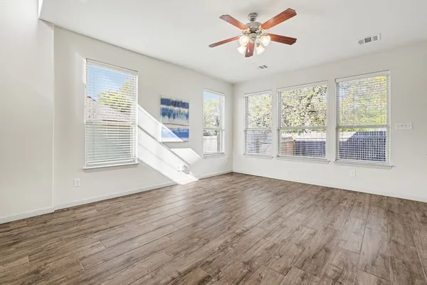a view of an empty room with wooden floor and a window