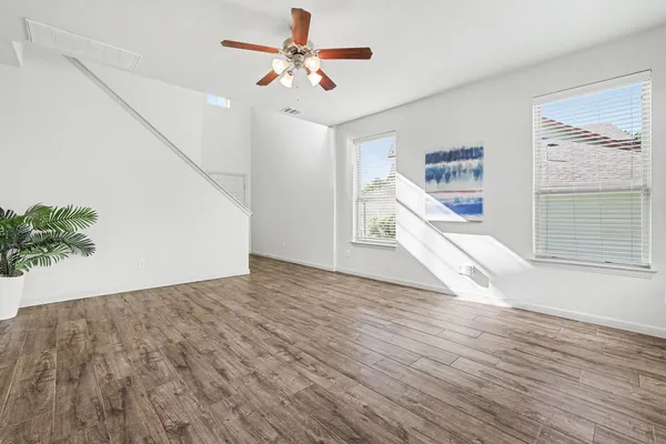 a view of empty room with wooden floor and fan