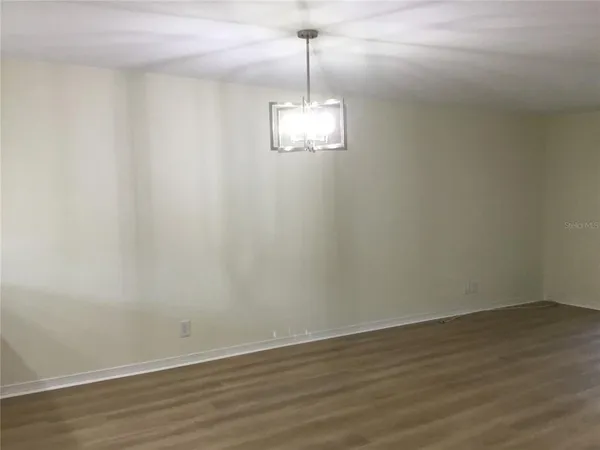 a room with a chandelier fan and wooden floor