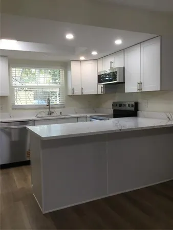 a kitchen with stainless steel appliances granite countertop a sink a stove a microwave a counter space and cabinets