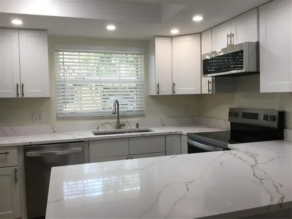 a kitchen with stainless steel appliances granite countertop a sink a stove top oven a counter space and cabinets