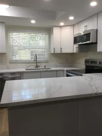 a view of kitchen with stainless steel appliances granite countertop a sink a stove and a microwave oven