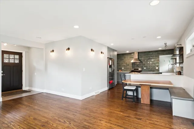 a living room with stainless steel appliances kitchen island granite countertop furniture and a wooden floor