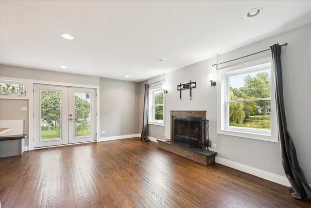 an empty room with wooden floor fireplace and windows