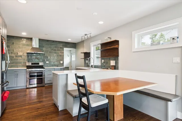 a kitchen with stainless steel appliances a dining table chairs microwave and sink