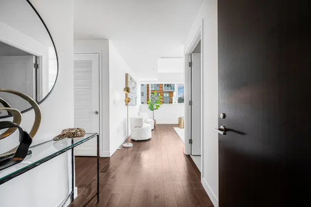 a view of a hallway with wooden floor and a livingroom