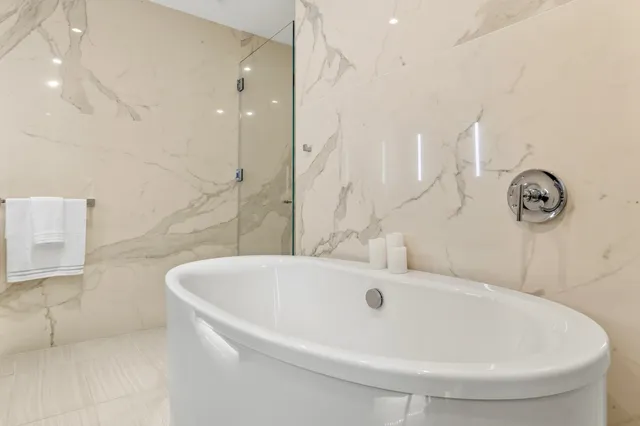 a white bath tub sitting in a bathroom and mirror