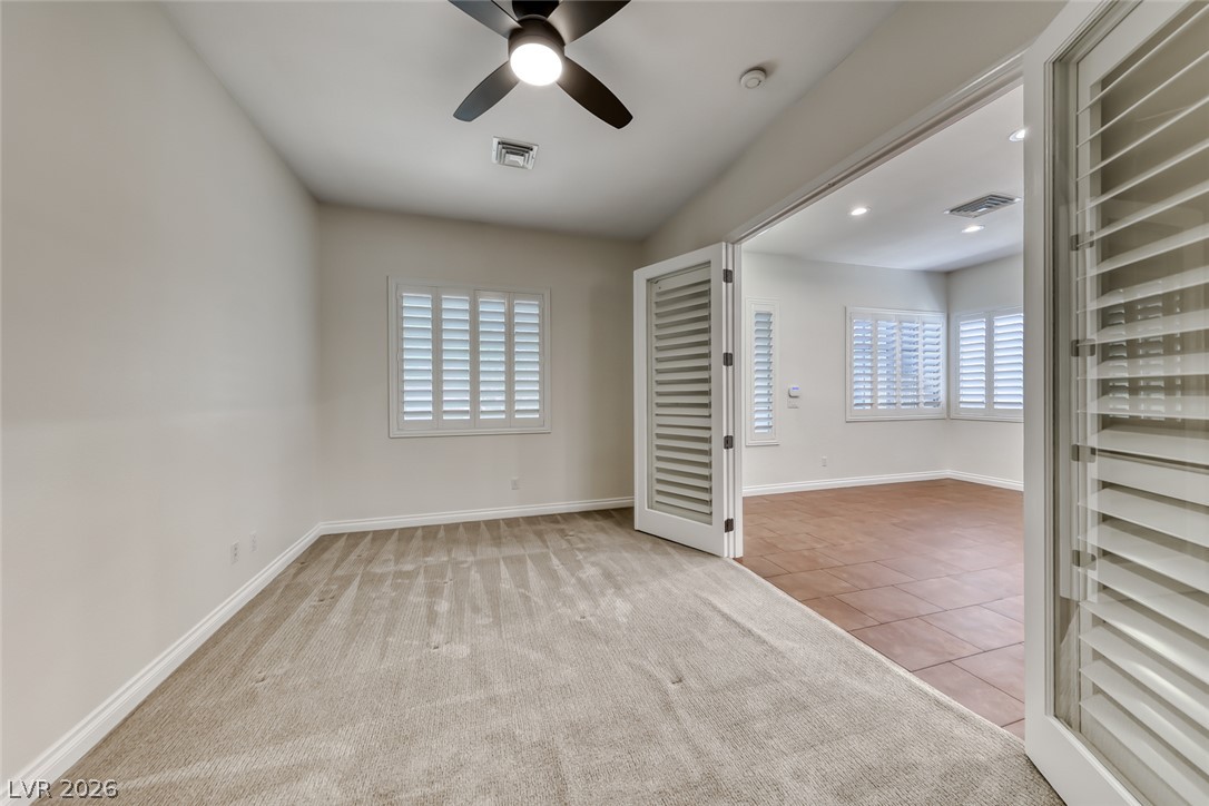 2122 Mooreview Street Henderson, NV 89012 - Photo 23 of 44 A versatile room with carpeted comfort, complemented by an adjacent space featuring tiled flooring and abundant natural light.