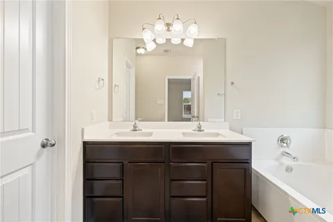 a bathroom with a double vanity sink mirror and bathtub