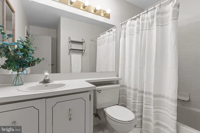 a bathroom with a sink a toilet a mirror and shower curtain