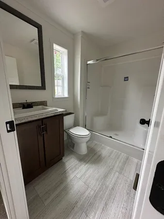 a bathroom with a sink a toilet a mirror and shower
