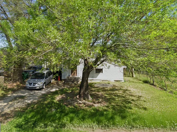 a view of a backyard with table and chairs and a large tree