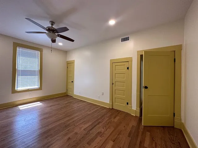 a view of empty room with wooden floor and fan