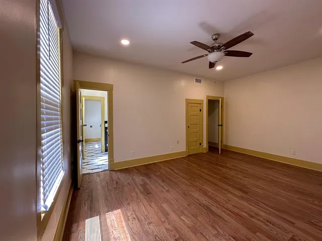 a view of empty room with wooden floor and fan