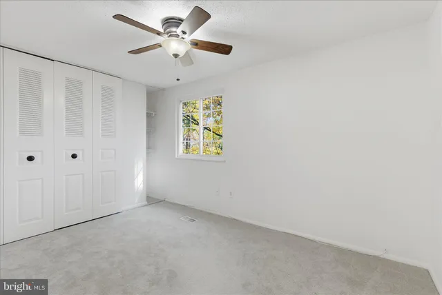 an empty room with a window and a fan
