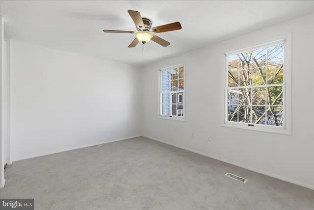 an empty room with a window and a ceiling fan