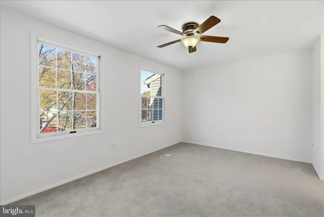 an empty room with chandelier fan and windows