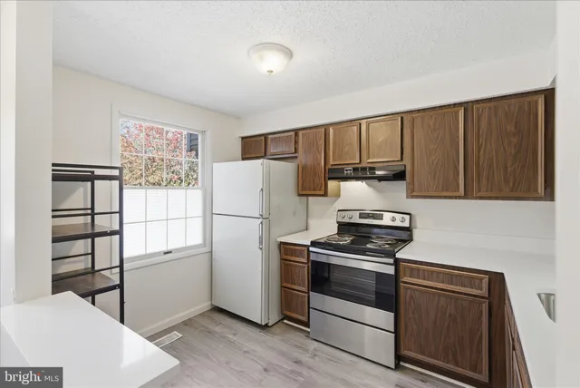 a kitchen with a refrigerator stove and wooden cabinets