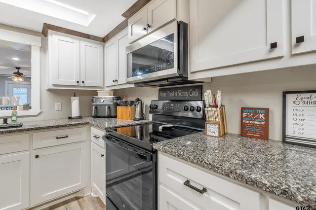 a kitchen with white cabinets and appliances